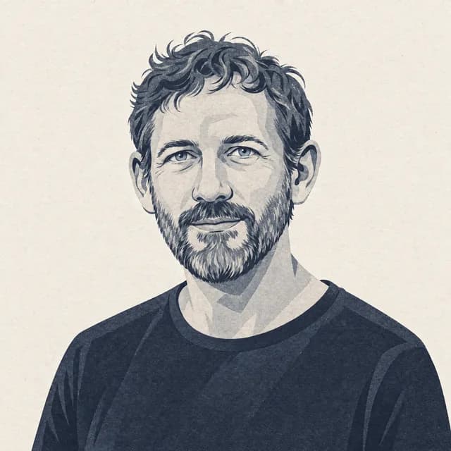 Tegnet portræt af Mads Nordskov: mand med kort krøllet hår og gråsprængt fuldskæg i mørk T-shirt