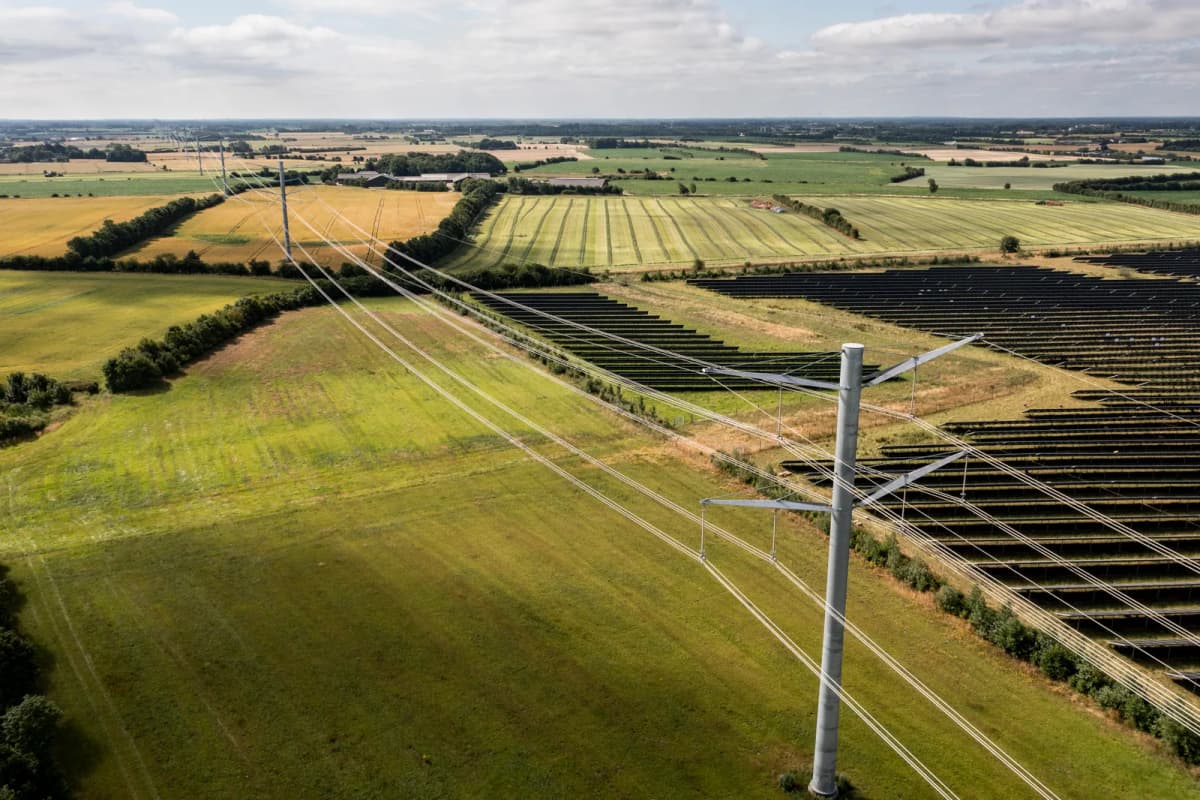Elmaster og luftledninger i dansk landskab med solceller